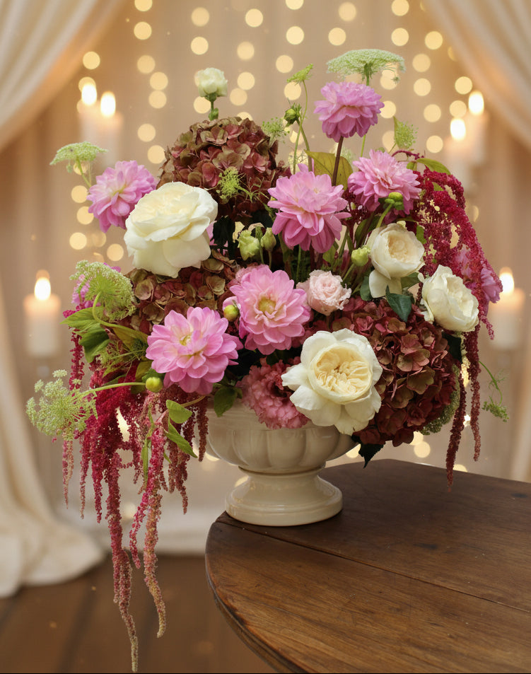 Grande composition florale rose et blanche avec roses, dahlias et fleurs retombantes pour un mariage.