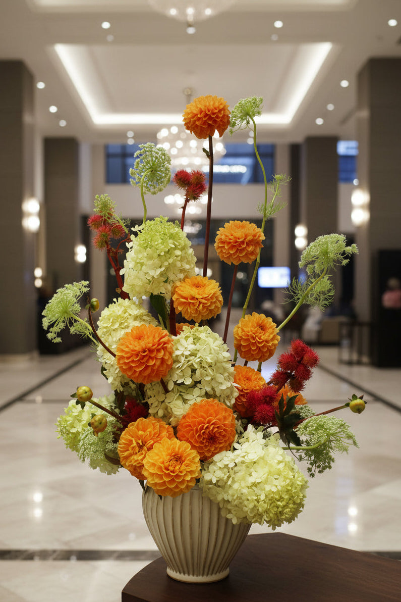 Composition florale élégante orange et verte dans un vase, idéale pour la décoration d'un hôtel ou d'un espace professionnel