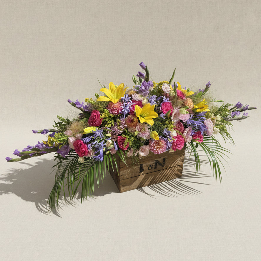 Raquette de fleurs colorées pour obsèques Dernier éclat réalisée par Arc en Ciel Fleurs. 