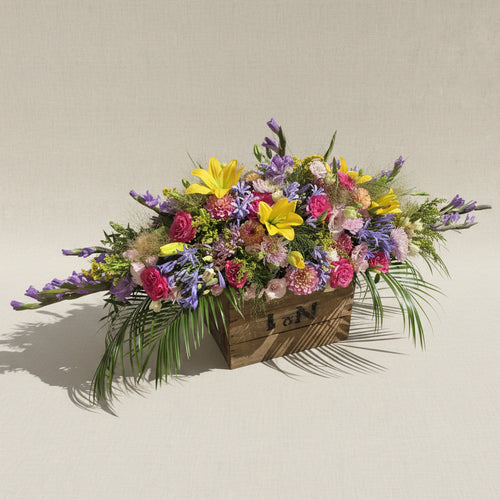 Raquette de fleurs colorées pour obsèques Dernier éclat réalisée par Arc en Ciel Fleurs. 